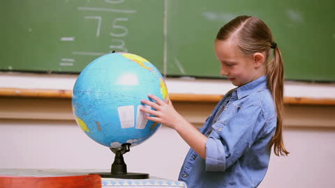 Young Student Exploring Globe in Classroom