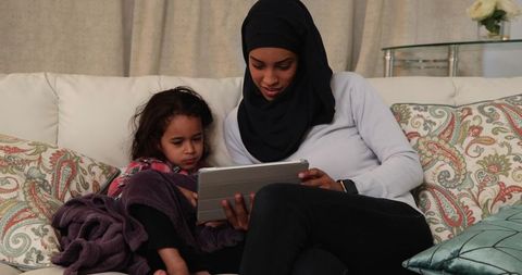 Young Mother in Hijab and Daughter Using Tablet Together at Home