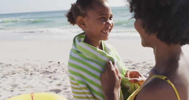 Mother wrapping daughter in beach towel at seaside - Download Free Stock Images Pikwizard.com