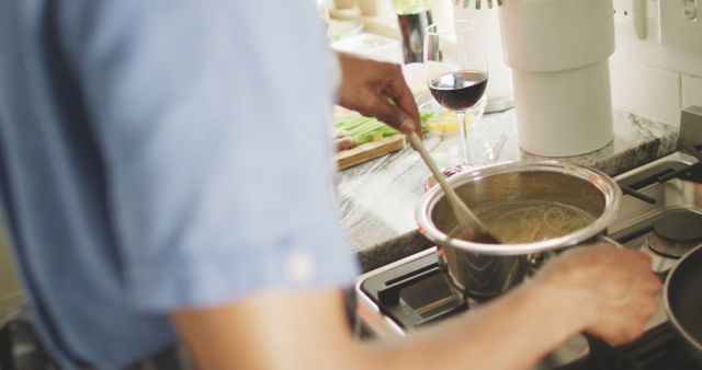 Person Cooking Pasta on Stove with Wine Glass in Kitchen - Download Free Stock Images Pikwizard.com