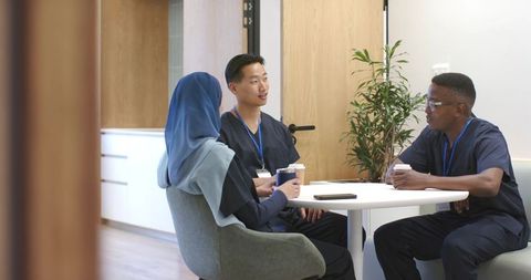 Multicultural healthcare team meeting over coffee in modern clinic staff lounge