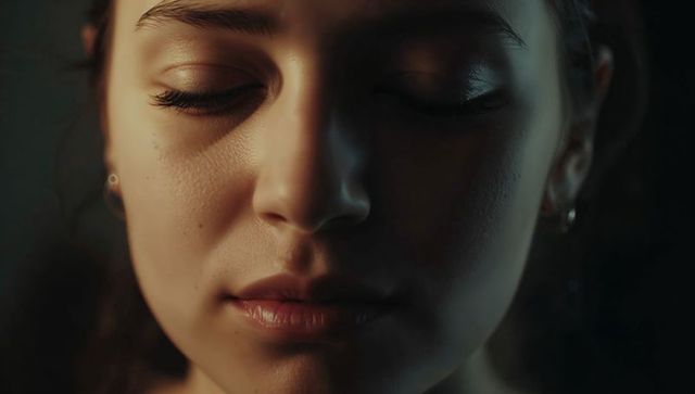 Closeup woman closing eyes showing natural skin texture in dramatic low-key chiaroscuro