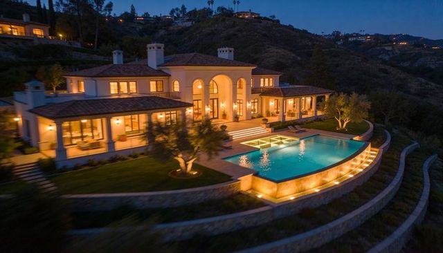 Mediterranean luxury villa glowing on hillside at dusk with infinity-edge pool and terraces