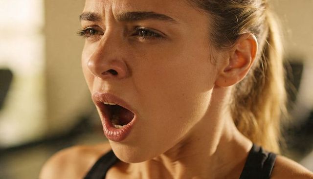 Woman athlete breathing heavily pushing through intense cardio workout determination