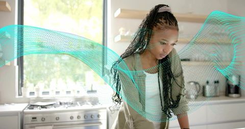 Young woman leaning and studying at smart kitchen counter with teal ar overlay