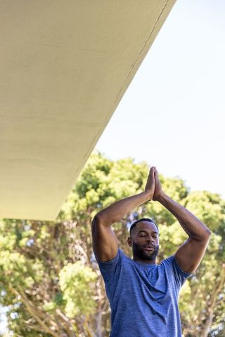 Mature african american man stretching outdoors under overhang practicing mindful yoga