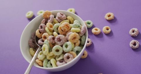 Colorful cereal rings in bowl on vibrant purple background