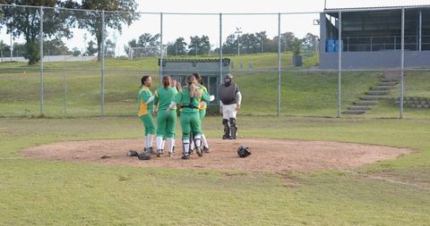 Female softball players celebrating with coach and catcher