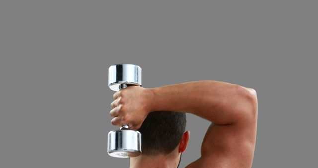 Man performing overhead tricep extension with dumbbell, highlighting arm muscles. Ideal for fitness and gym promotions, instructional content on strength training, or materials focused on bodybuilding and physical health.