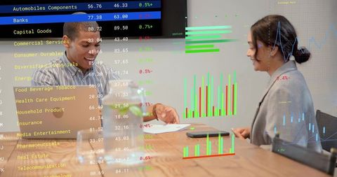 Colleagues reviewing financial reports with laptop and interactive charts in boardroom
