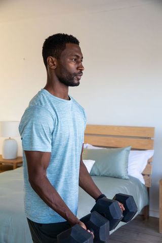 Focused Man Exercising at Home with Dumbbells