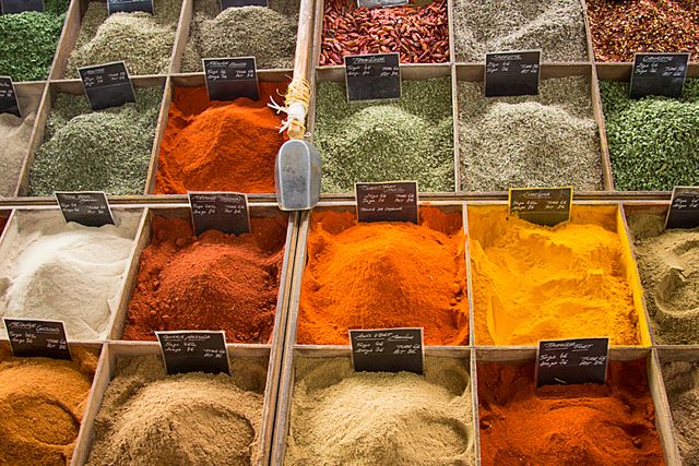 Colorful assortment of spices displayed in rows in market, showcasing red, yellow, green, and brown powders. Ideal for images of culinary culture, food markets, produce, and cooking backgrounds. Perfect for articles on cooking, spice use, travel experiences in public markets, and culinary traditions.
