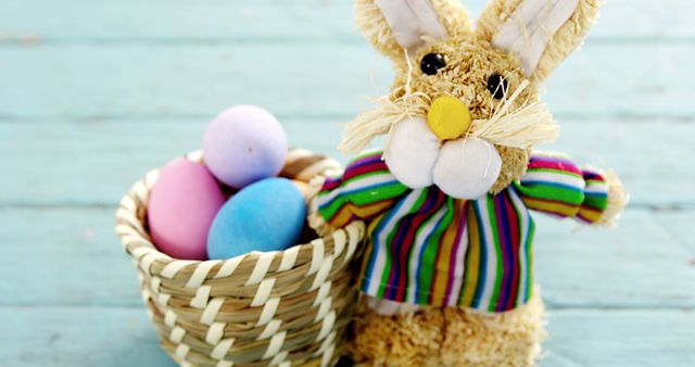 A straw Easter bunny toy is accompanied by a basket filled with colorful eggs, with copy space. Easter celebrations often include such decorations symbolizing rebirth and new beginnings.
