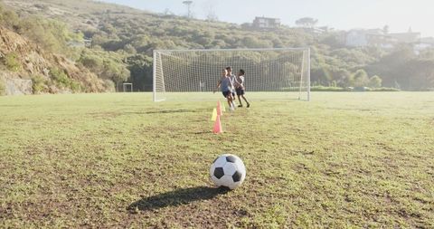 Children Playing Soccer on Sunny School Field with Goalposts