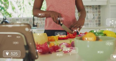 Woman chopping colorful peppers on kitchen counter with tablet and social media overlays
