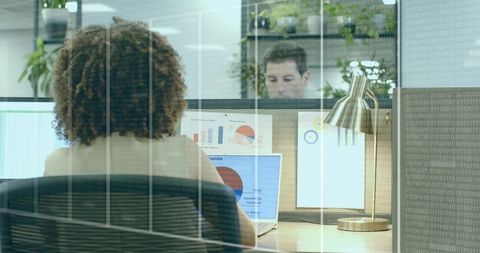 Curly-haired professional analyzing laptop data in modern office