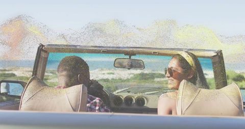 Couple cruising convertible along sunny coastline enjoying road trip and ocean views
