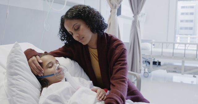 Mother comforting her sick daughter in hospital bed with an oxygen mask. Shows strong family bond and care during difficult times. Useful for healthcare, family support and hospital care themes.