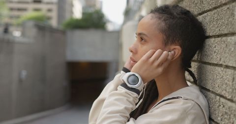Young Woman with Earphones in Urban Environment Listening to Music