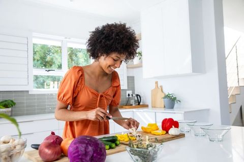 Woman in Orange Dress Cutting Vegetables in Modern Kitchen