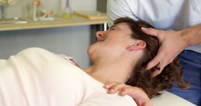 Chiropractor performing a neck adjustment on a female patient lying down. Useful for illustrating chiropractic services, healthcare articles, physiotherapy brochures, and wellness promotion content.