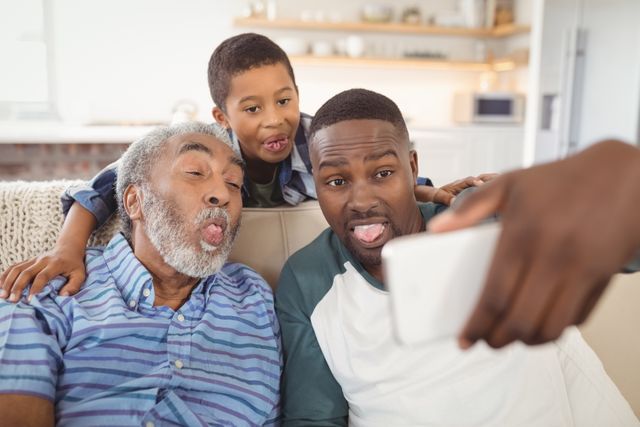Smiling multi-generation family taking selfie from mobile phone in living room at home