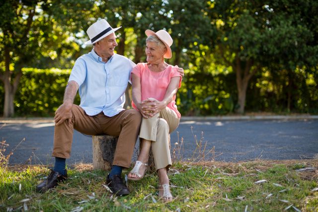 Smiling senior couple sitting on rock by road