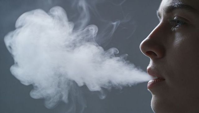 Female profile exhaling dense vapor plume closeup portrait for vaping, breath, health concept