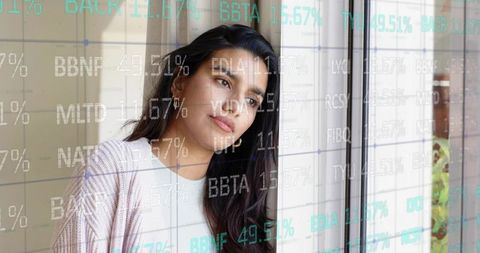 Gazing midadult woman viewing stock ticker overlays through home glass door