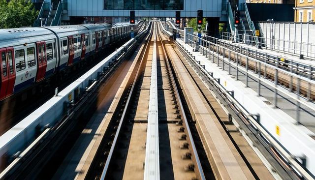 Elevated commuter rail tracks stretching into urban transit corridor with passing train