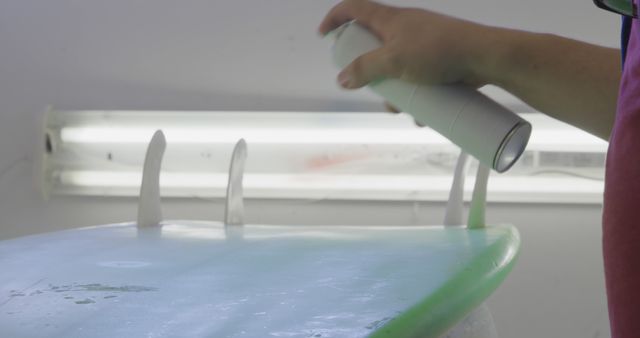 Person Spraying Surfboard With Paint Near Light Fixture - Download Free Stock Images Pikwizard.com