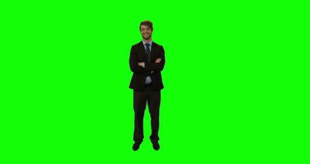 A confident businessman in a formal suit stands with his arms crossed against a green screen background. This can be used for presentations, business promotions, advertising, or any creative projects requiring easy background removal. Ideal for corporate branding and professional business visuals.