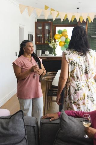 African american women chatting at home celebration holding wine glasses with balloons
