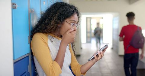 Teenage Girl Reacting to Phone Message in School Hallway