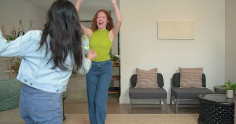 Friends greeting and laughing in bright living room with modern decor and plants