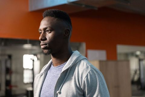 Young man checking gym mirror after offscreen clatter, assessing equipment and focus