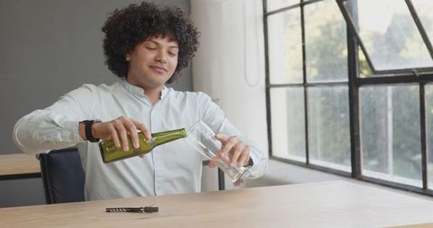 Man Enjoying Refreshing Beverage at Work Desk During Break