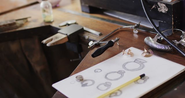 Close up of tools and sketches on wooden table in jewellery workshop. Jewellery, tools, enterpreneurship and small business.