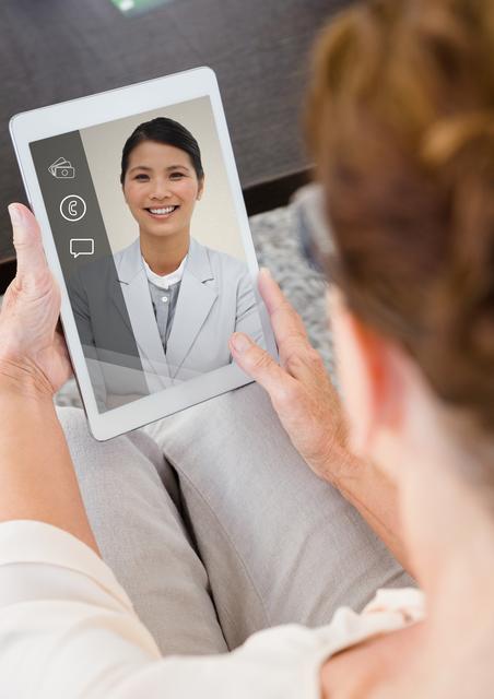 Senior woman engaging in a video chat on a digital tablet, highlighting modern technology in elderly life. Useful for illustrating topics such as virtual communication, technology adoption among seniors, healthcare teleconference, or remote familial connections.