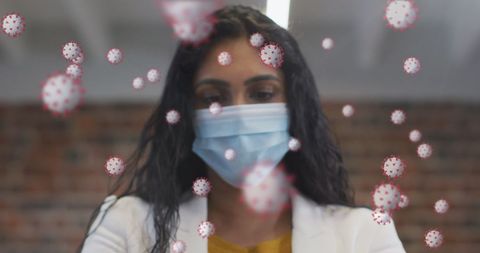 Woman in face mask amid floating covid-19 cells in office