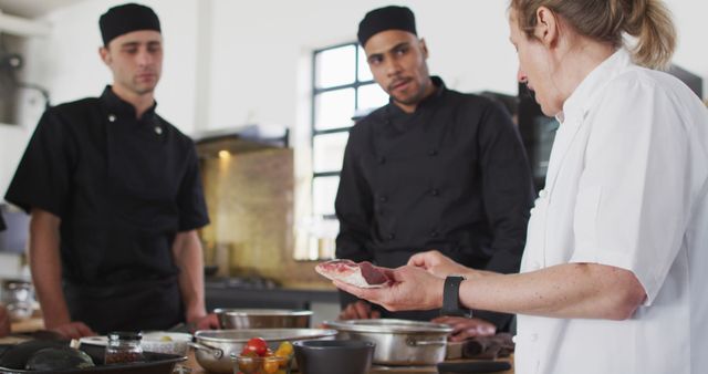 Experienced chef training next generation of cooks in modern kitchen environment. Ideal for illustrating culinary education, professional cooking, mentorship in restaurant industry, team collaboration, culinary school advertising.