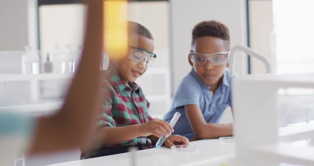 Image of happy african american boys wearing glasses during chemistry lesson. primary school education and learning concept.