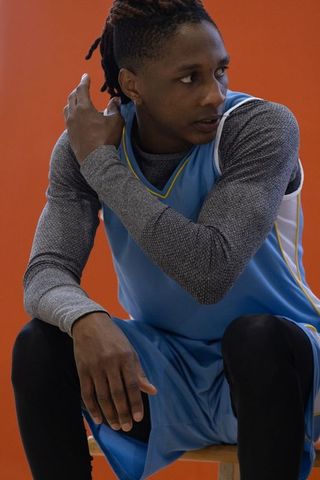 Young african american athlete in blue jersey adjusting dreadlocks