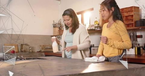 Mother teaching teen cleaning techniques on sunlit rustic kitchen island