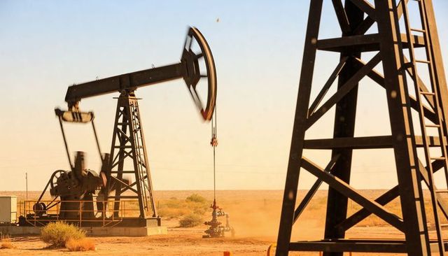 Desert pumpjack pumping oil on remote plain with dust and steel towers