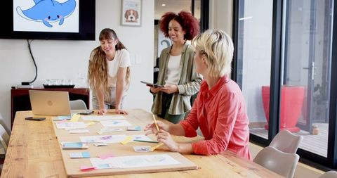Creative female team collaborating on ideas with mockups and sticky notes