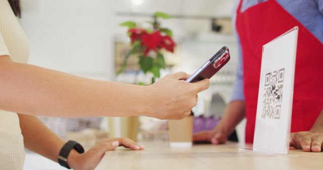 Customer scanning QR code with smartphone for contactless payment in store. Ideal for use in articles about modern retail technology, mobile payments, cashless transactions, safety measures during covid-19, and trends in shopping behavior.