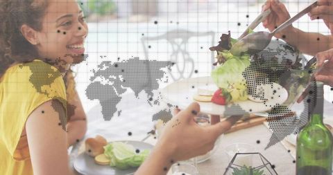 Smiling woman holding plate while friends serve salad at sunlit patio dinner gathering