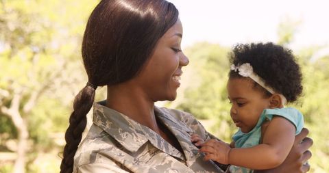 African American Female Soldier Holding Young Child Outdoors