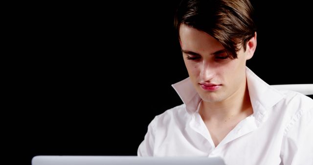 Young Man Focused on Laptop Work Against Black Background - Download Free Stock Images Pikwizard.com